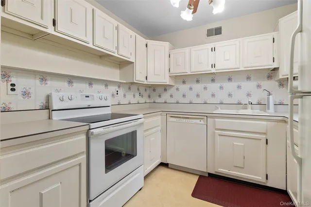 a kitchen with granite countertop white cabinets and white appliances