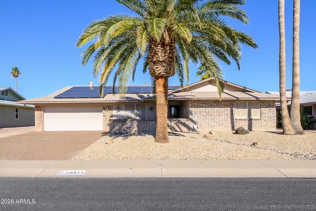 a view of a house with a yard and palm trees