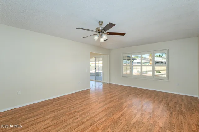 a view of an empty room with window and wooden floor