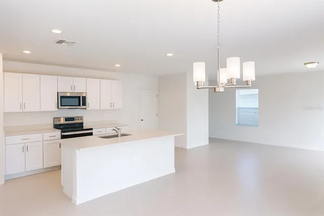 a kitchen with stainless steel appliances kitchen island granite countertop a refrigerator a stove a sink and a microwave