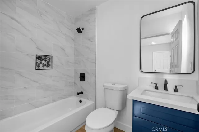a bathroom with a bathtub shower sink vanity mirror and toilet