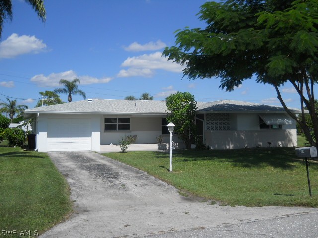 803 East Bougainvillea Road Lehigh Acres, FL 33936 - Photo 2 of 20 a front view of a house with a garden and a tree
