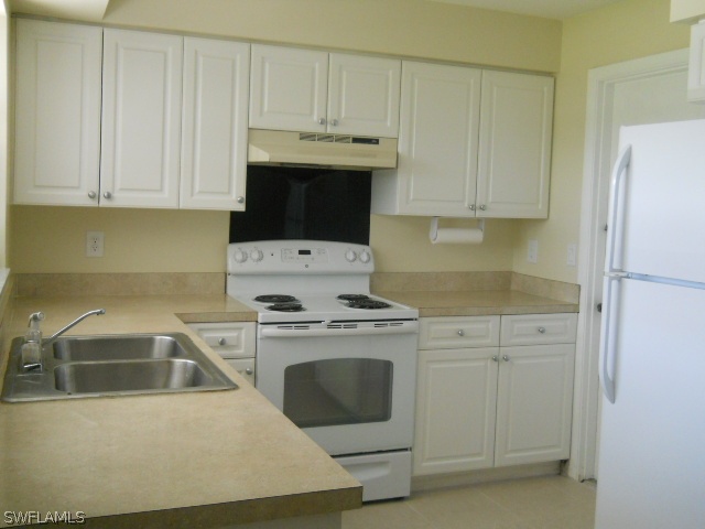 803 East Bougainvillea Road Lehigh Acres, FL 33936 - Photo 6 of 20 a kitchen with white cabinets and stainless steel appliances