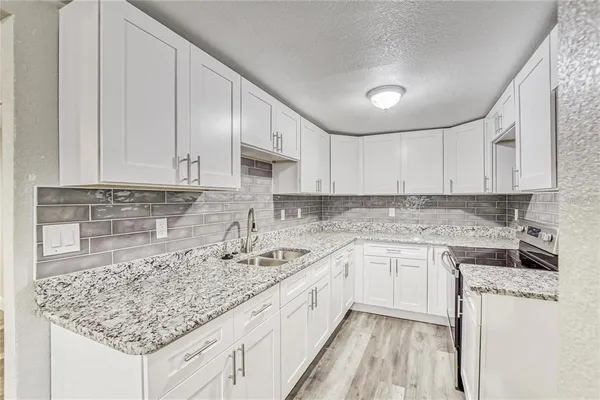 a kitchen with stainless steel appliances granite countertop a sink stove and white cabinets