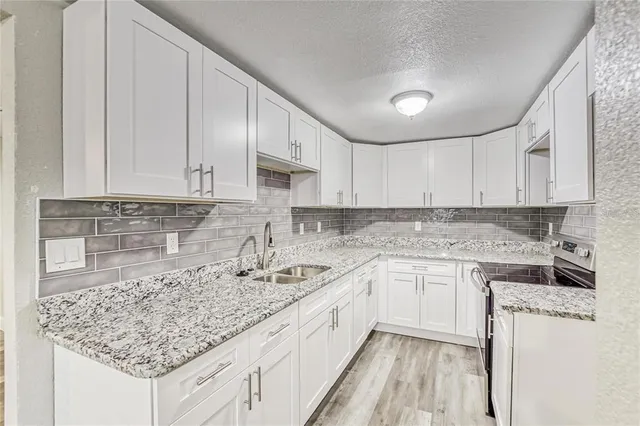 a kitchen with stainless steel appliances granite countertop a sink stove and white cabinets