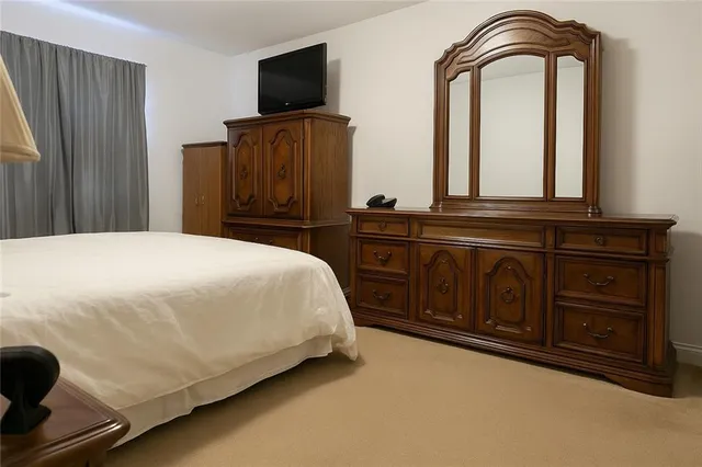 a bedroom with a bed and flat tv screen on the dresser