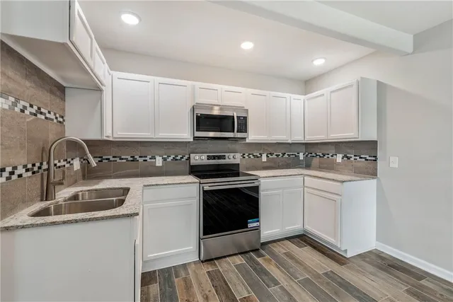 a kitchen with granite countertop white cabinets and stainless steel appliances