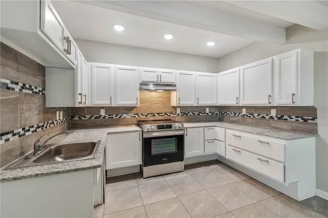a kitchen with granite countertop white cabinets and white appliances
