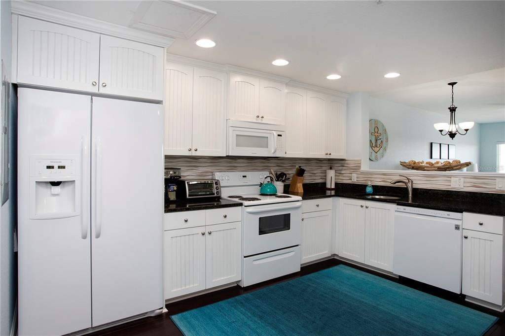399 2nd Street, Unit 417 Indian Rocks Beach, FL 33785 - Photo 6 of 35 a kitchen with white cabinets and sink