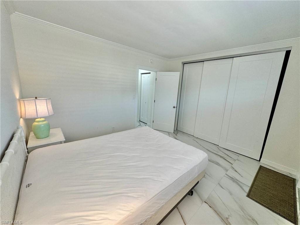 473 12th Avenue South, Unit B7 Naples, FL 34102 - Photo 12 of 21 Bedroom featuring a closet, light tile flooring, and ornamental molding