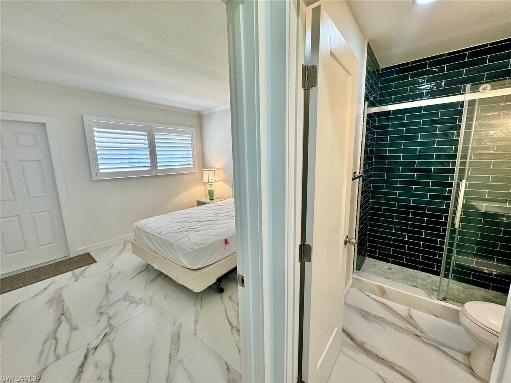 473 12th Avenue South, Unit B7 Naples, FL 34102 - Photo 14 of 21 Bathroom with tile floors, a shower with door, ornamental molding, and toilet