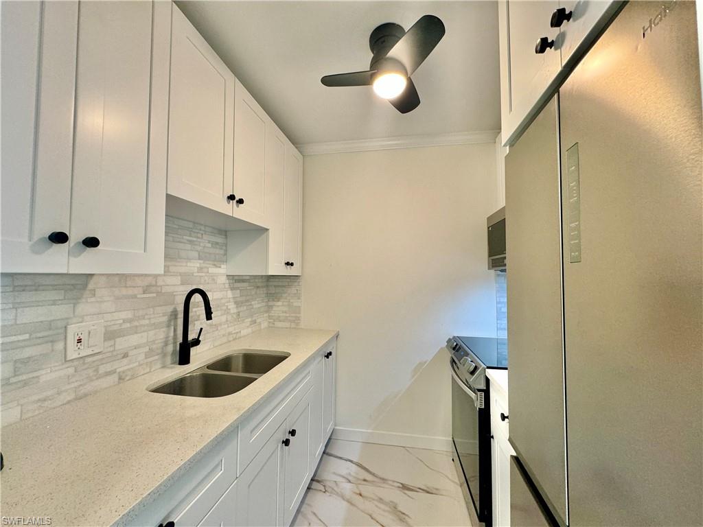 473 12th Avenue South, Unit B7 Naples, FL 34102 - Photo 4 of 21 Kitchen featuring light tile flooring, backsplash, sink, white cabinetry, and appliances with stainless steel finishes