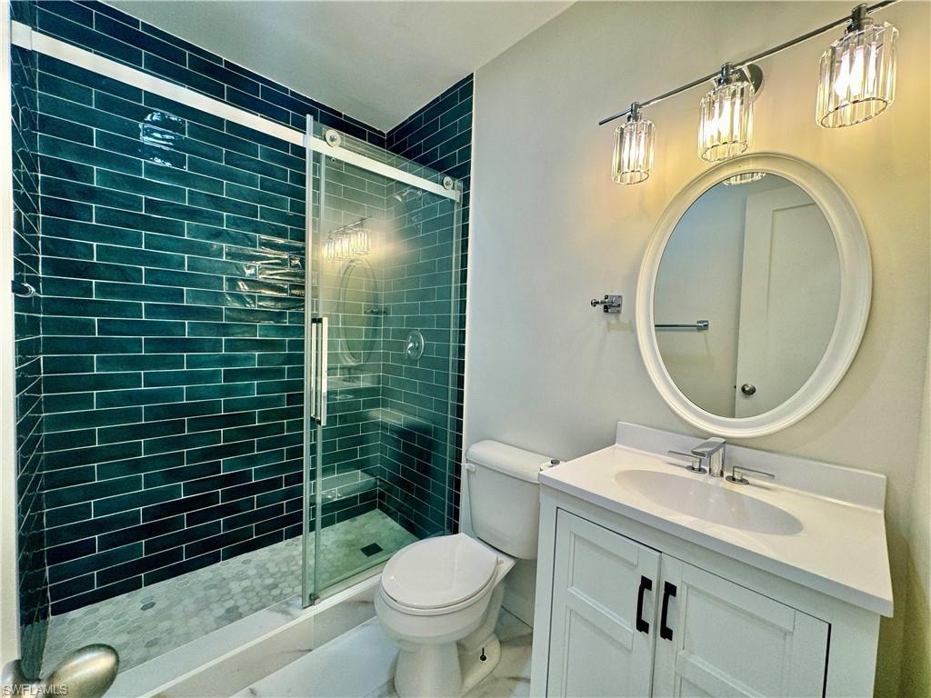 473 12th Avenue South, Unit B7 Naples, FL 34102 - Photo 8 of 21 Bathroom with tile floors, an enclosed shower, oversized vanity, and toilet