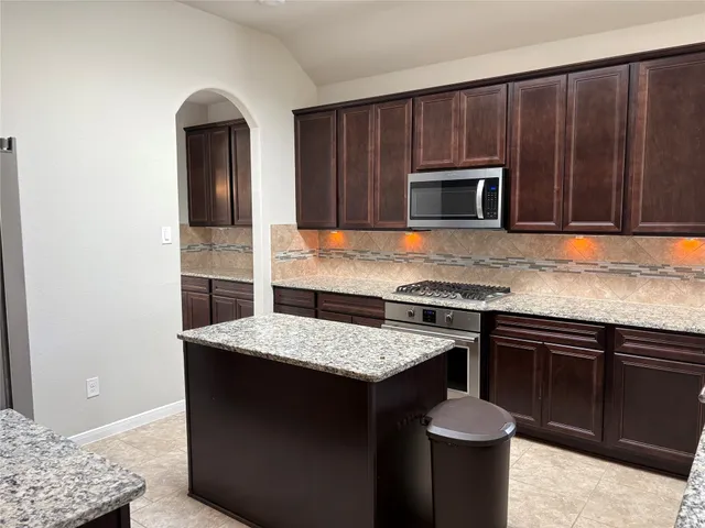 a kitchen with stainless steel appliances granite countertop a stove a sink and a microwave