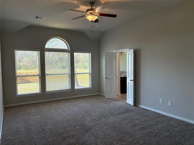 an empty room with chandelier fan and windows