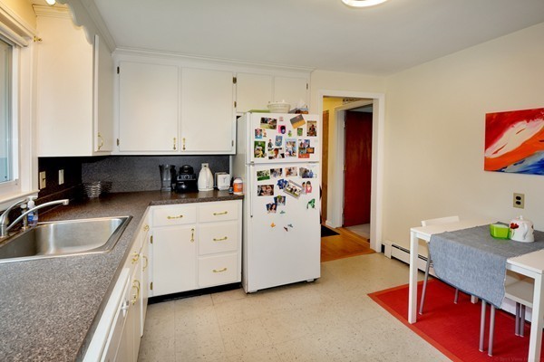 7-9 Sparkill Street Watertown, MA 02472 - Photo 26 of 27 a kitchen with stainless steel appliances granite countertop a sink a stove a refrigerator a white table and chairs with wooden floor