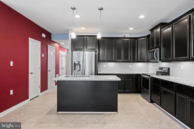 a large kitchen with stainless steel appliances kitchen island granite countertop a refrigerator and a sink