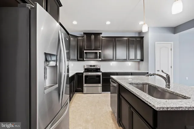a kitchen with kitchen island granite countertop a sink stainless steel appliances and cabinets