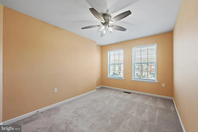 a view of an empty room with chandelier fan and a window