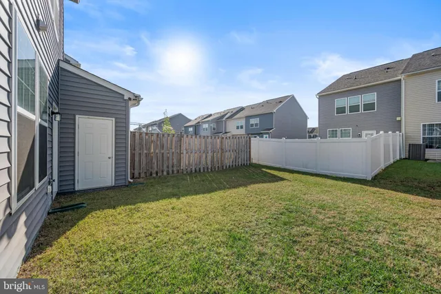 a view of backyard with barbeque grill and wooden fence