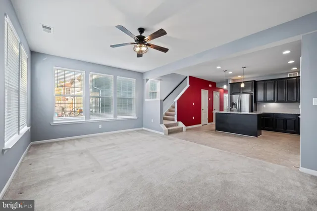 a view of an empty room with a window and a kitchen