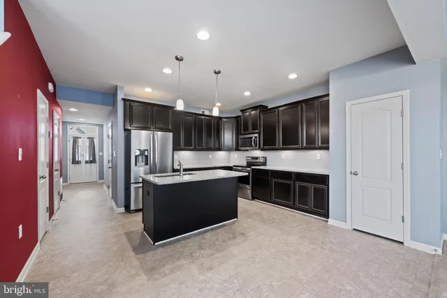 a kitchen with stainless steel appliances kitchen island granite countertop a refrigerator and a sink