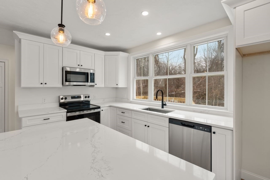 52 Freeman Street Avon, MA 02322 - Photo 3 of 17 a kitchen with granite countertop a stove a sink a microwave and wooden cabinets