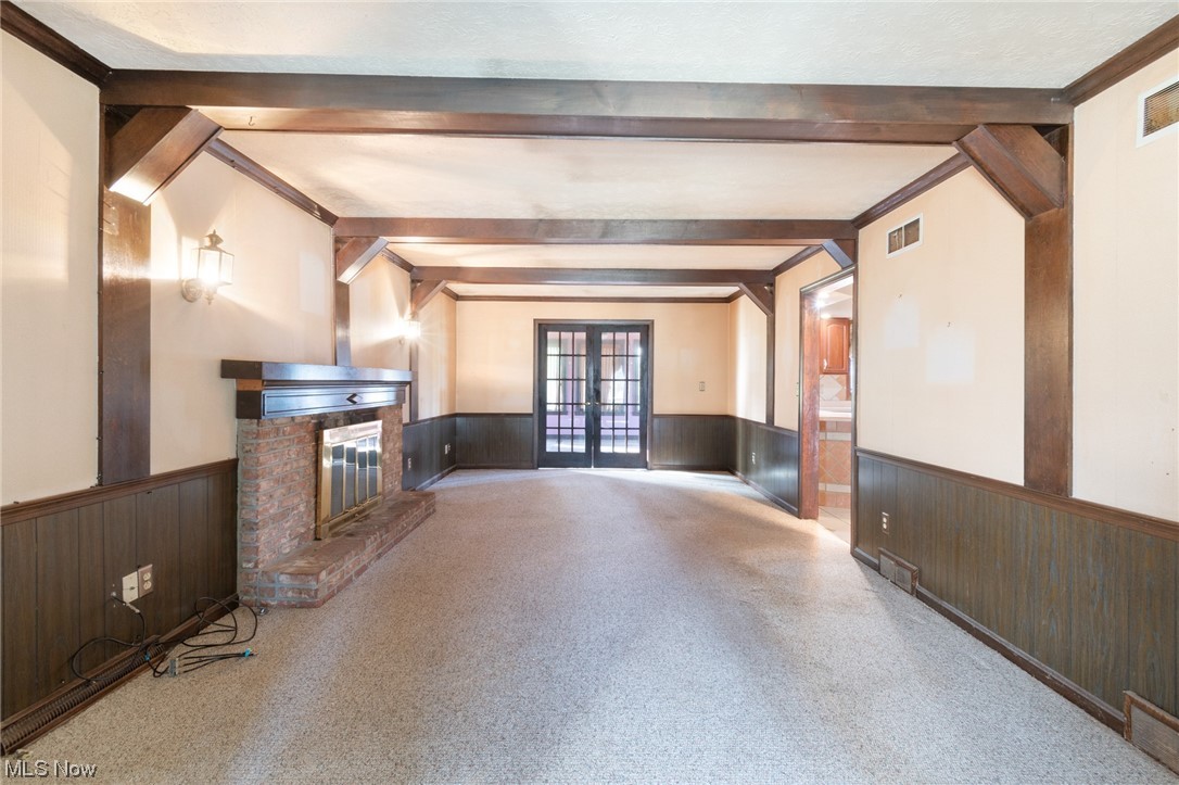 6038 Tippecanoe Road Canfield, OH 44406 - Photo 10 of 34 Unfurnished living room with beams, light colored carpet, a brick fireplace, and french doors