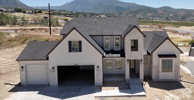 French provincial home with a mountain view, driveway, stucco siding, and a shingled roof