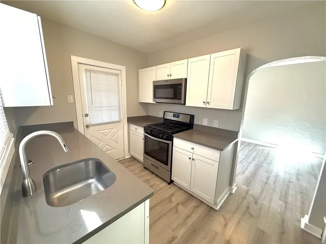 a kitchen with granite countertop a stove a sink and a microwave