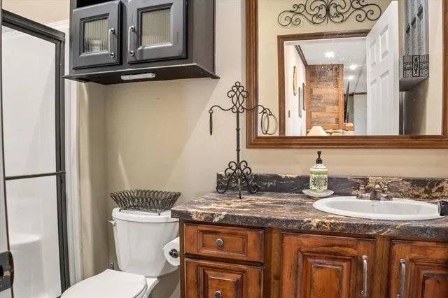 a bathroom with a granite countertop toilet sink and mirror