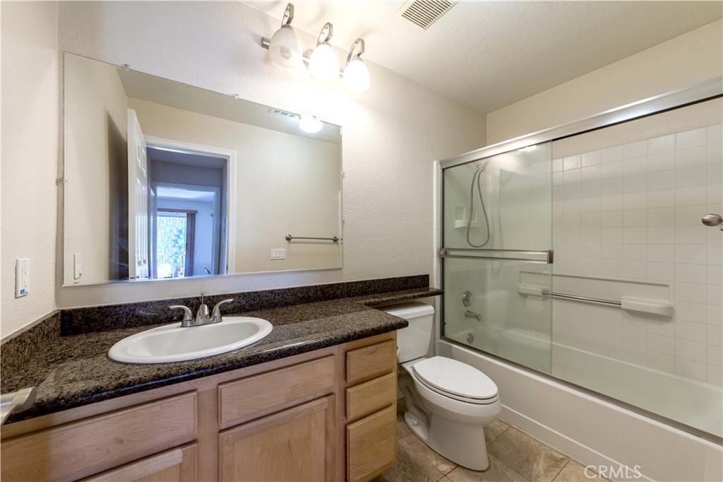 a bathroom with a granite countertop sink toilet a mirror and shower