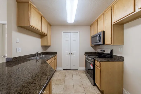 a kitchen with granite countertop a sink stove and cabinets