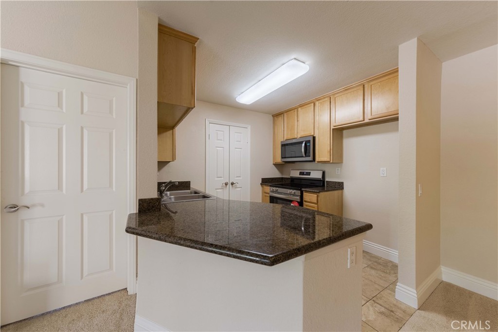 2400 Del Mar Way, Unit 207 Corona, CA 92882 - Photo 9 of 20 a kitchen with granite countertop a refrigerator a stove and a sink