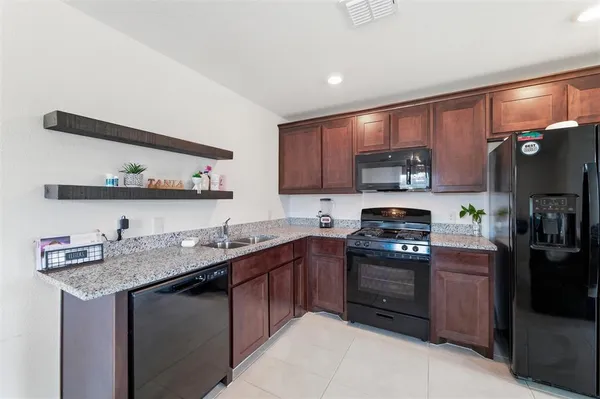 a kitchen with stainless steel appliances granite countertop a sink dishwasher stove and refrigerator