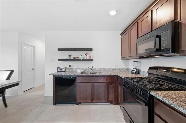 a kitchen with stainless steel appliances granite countertop a stove top oven a sink dishwasher and cabinets with wooden floor