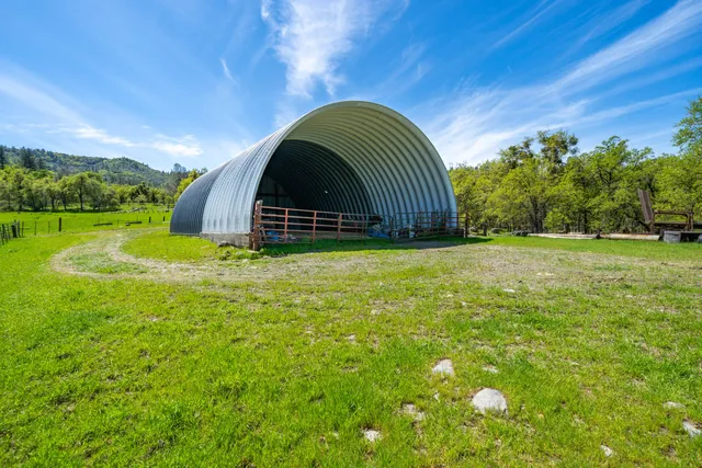 a view of a lush green outdoor space with a swimming pool and valleys in the background