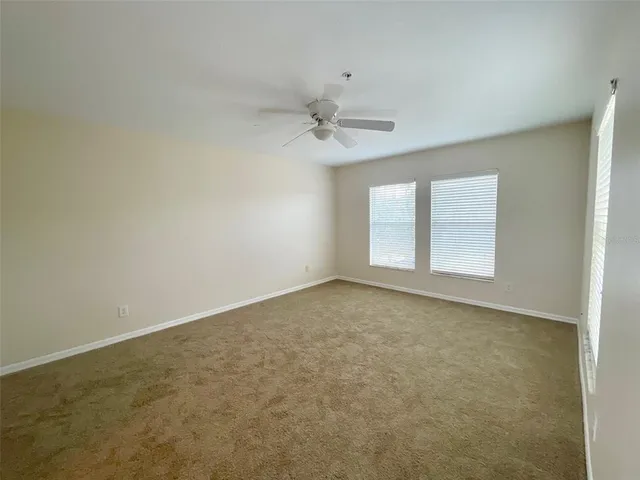 an empty room with windows and fan