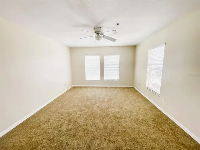 an empty room with a window and a ceiling fan