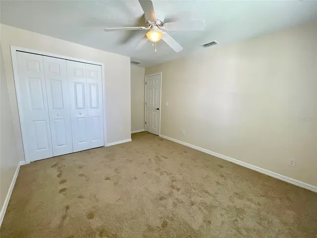 an empty room with a fan & a ceiling fan
