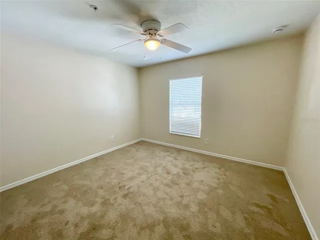 an empty room with a chandelier fan and windows
