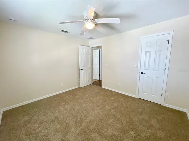 an empty room with a ceiling fan and a window