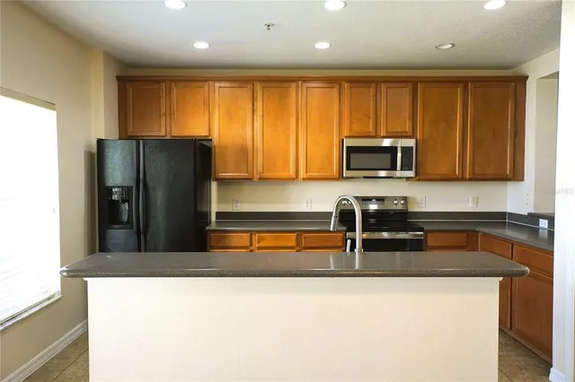 a kitchen with granite countertop wooden cabinets a refrigerator and a sink