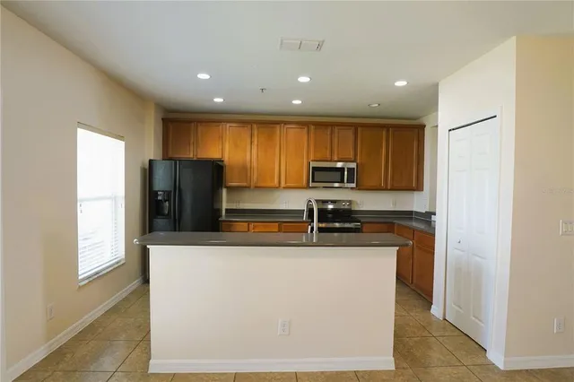 a kitchen with stainless steel appliances granite countertop a refrigerator a stove a sink a microwave a refrigerator and white cabinets with wooden floors