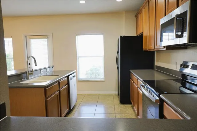 a kitchen with stainless steel appliances granite countertop a sink a stove a microwave a refrigerator and a microwave