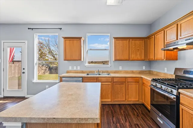 a kitchen with stainless steel appliances granite countertop a stove a sink and a microwave