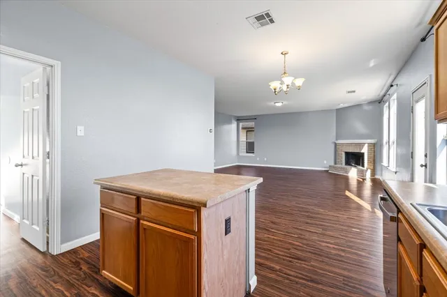 a room with kitchen island a stove and wooden floor