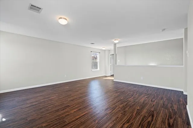 a view of an empty room with wooden and a window