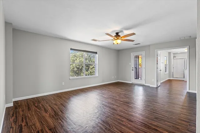 a view of an empty room with window and wooden floor