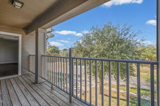 a view of a balcony with wooden floor & fence